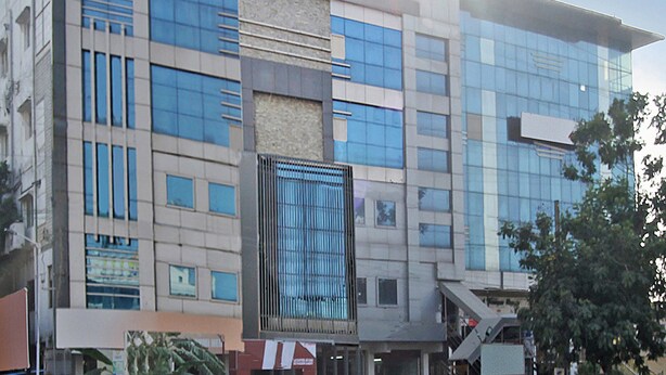 Un immeuble moderne à plusieurs étages, doté de grandes fenêtres et d’une façade combinant verre et béton.