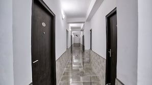 A long, narrow hallway with marble flooring and dark wooden doors on either side.