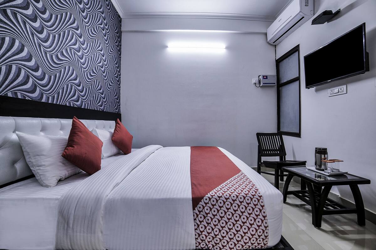 Habitación de hotel con cama, una silla, una mesa y un televisor.