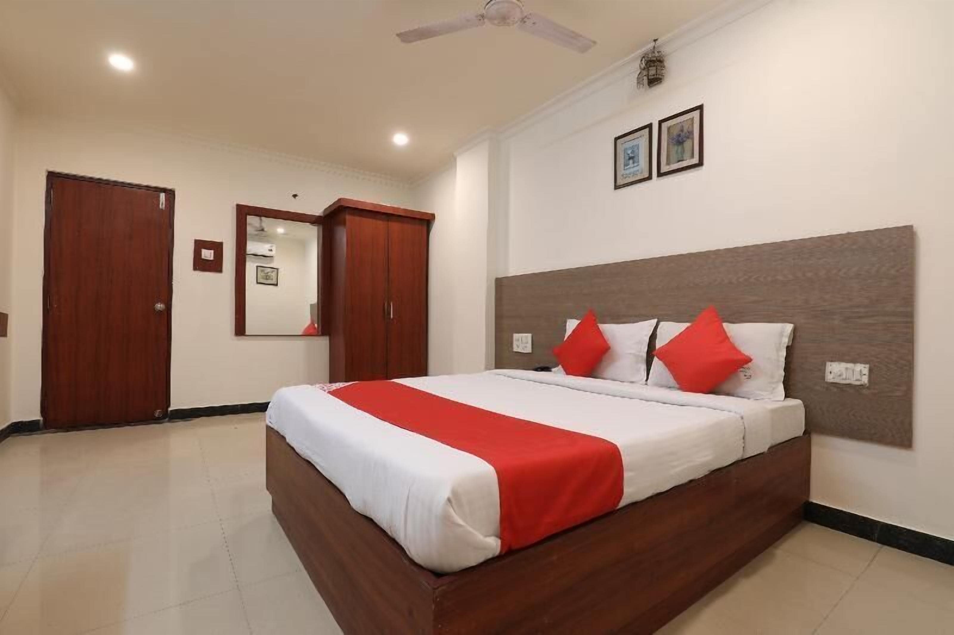A hotel room with a large bed, wooden headboard, and a ceiling fan.