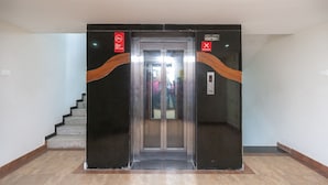 An elevator with a modern design, featuring a control panel and emergency stop button. - OYO 19909 Sri Guru Inn (Coimbatore)