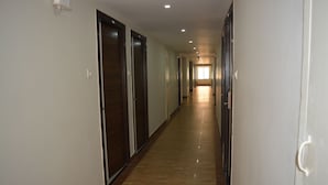 A long, narrow hallway with doors on both sides, leading to a bright room at the end. - OYO 19909 Sri Guru Inn (Coimbatore)