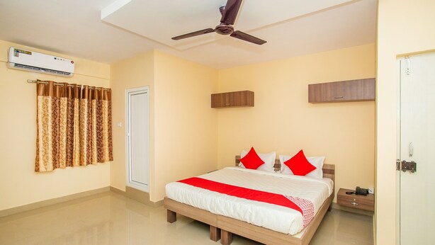 Una habitación de hotel con cama, ventilador de techo, aire acondicionado, armario y mesita de noche.