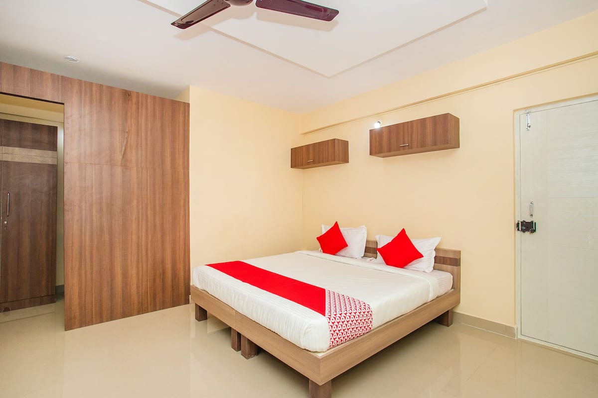 A bedroom with a bed, wooden wardrobe, and a door.