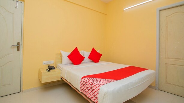 A bedroom with a bed, nightstand, and two doors. - OYO 10522 Varcity Emerald (Bengaluru)