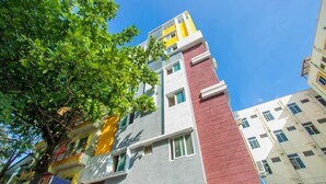 A multi-story building with a mix of red, yellow, and grey exterior walls, balconies, and windows. - OYO 10522 Varcity Emerald (Bengaluru)