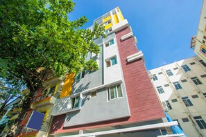 A multi-story building with a mix of red, yellow, and grey exterior walls, balconies, and windows. - OYO 10522 Varcity Emerald (Bengaluru)