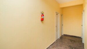 Un passadís amb parets grogues, un extintor fixat a la paret i dues portes blanques al final.