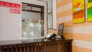 A reception desk with a computer monitor, a glass partition, and a wall-mounted air conditioning unit. - OYO 12693 Manori Resort (Gorai)