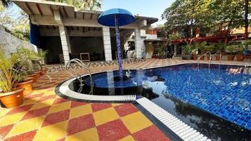 A swimming pool with a tiled floor and a blue umbrella.