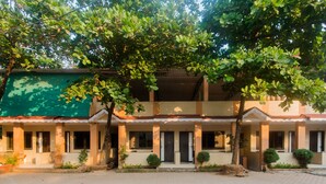 A two-story building with a covered entrance, multiple windows, and a paved courtyard. - OYO 12693 Manori Resort (Gorai)