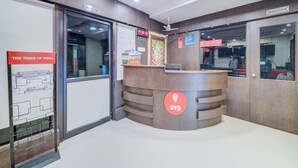 A reception desk with a digital clock, a sign for 'OYO Rooms', and a 'No Smoking' sign. - OYO Flagship 24397 9 Star Hotel (Hyderabad)
