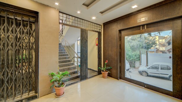 A lobby with a staircase, potted plants, and a view of the outside. - OYO Flagship 24397 9 Star Hotel (Hyderabad)