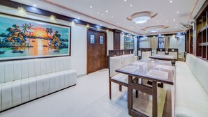 A modern dining area with a large mural, cushioned seating, and a long table. - OYO Flagship 24397 9 Star Hotel (Hyderabad)