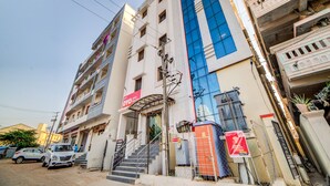 A multi-story hotel with a prominent blue glass facade, a visible staircase, and a sign indicating the presence of a hotel and a restaurant. - OYO Flagship 24397 9 Star Hotel (Hyderabad)