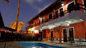 Ein zweistöckiges Gebäude mit Balkon, Swimmingpool und Außenmöbeln.