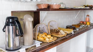 Ein Buffet mit Kaffeemaschine, Wasserspender und Körben mit Brot und Gebäck.