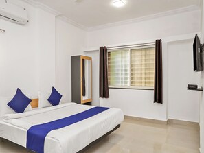 A hotel room with a bed, a wardrobe, a window with curtains, a flat-screen TV, and an air conditioning unit. - OYO 19530 SilverKey Vishrantwadi (Pune)