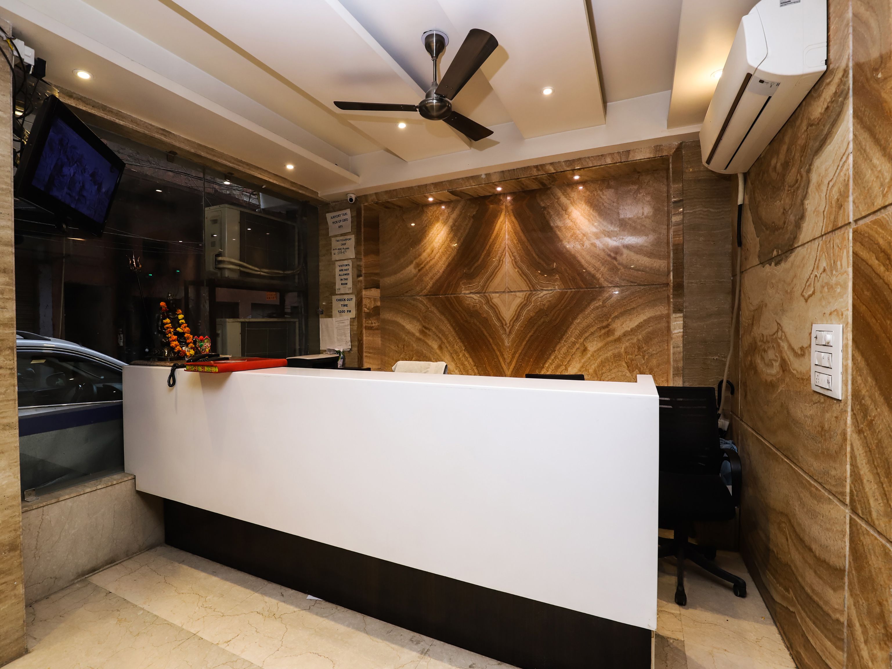 A reception desk with a modern design, a ceiling fan, and an air conditioning unit on the wall.