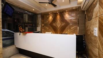 A reception desk with a modern design, a ceiling fan, and an air conditioning unit on the wall.