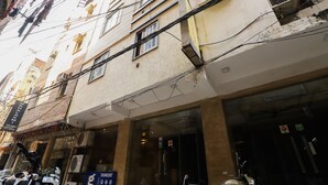 A multi-story building with a ground-floor shop, multiple balconies, and a visible air conditioning unit. - OYO 24677 Tashkent (New Delhi)