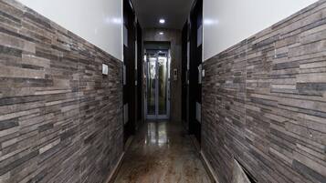 A hallway with stone-patterned walls and a polished floor, leading to a door with a glass panel.