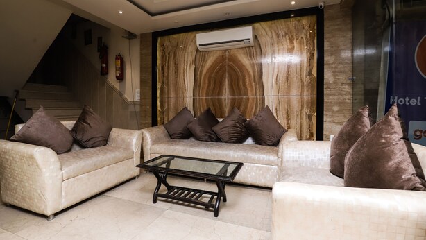 A hotel lobby with a modern design, featuring a sofa set, a glass coffee table, and a ceiling fan. - OYO 24677 Tashkent (New Delhi)