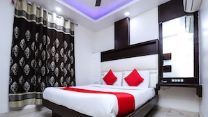 A modern bedroom with a large bed, a mirror, and a ceiling light. - OYO 24677 Tashkent (New Delhi)