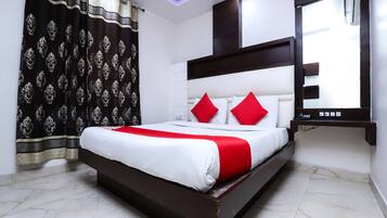 A modern bedroom with a large bed, a mirror, and a ceiling light.