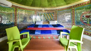 A circular room with a bed, green chairs, and a tiled wall with a geometric pattern. - OYO 24424 Kf Resorts Pvt Ltd (Jaisalmer)