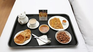 A tray with a teapot, cups, a plate of flatbread, a bowl of soup, a plate of flatbread, a bowl of nuts, and a menu. - OYO 24424 Kf Resorts Pvt Ltd (Jaisalmer)