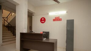 Ein Empfangstresen mit einem Schild, einem Feuerlöscher und einer Treppe im Hintergrund.
