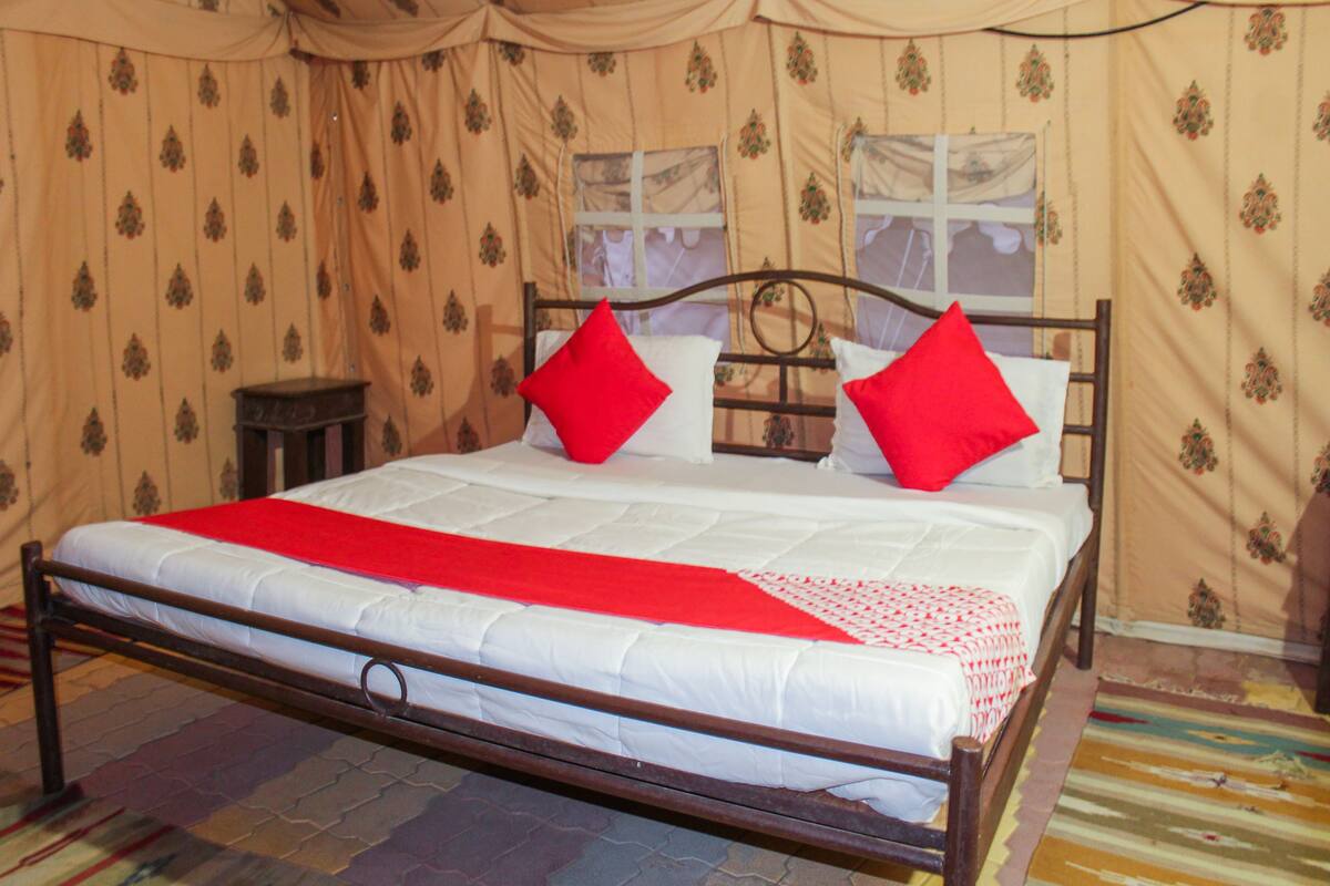 Un lit avec une couverture et des oreillers rouges, une tête de lit en bois et un mur à motifs.