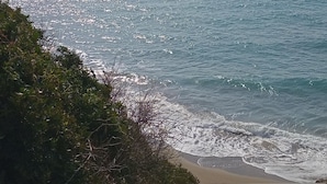 A coastal landscape with a beach, rocky cliffs, and a distant island. - Helena Inn (Kefalonia)