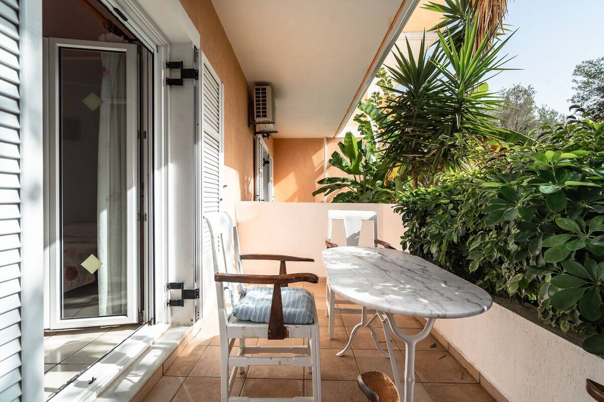 A patio with a white table and chairs, a sliding glass door, and a wall-mounted air conditioning unit.