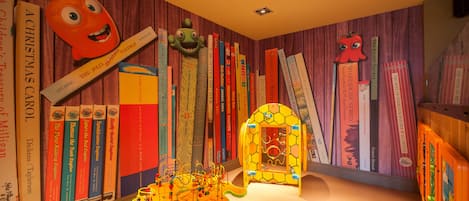 A children's library with bookshelves, a large cartoon character, and a play area.