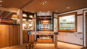 A modern kitchen with a built-in oven, a wooden table, and a window displaying menu items. - Canterbury Bell, Margate by Marston's Inns (Broadstairs)