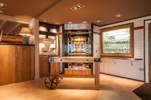 A modern kitchen with a built-in oven, a wooden table, and a window displaying menu items.