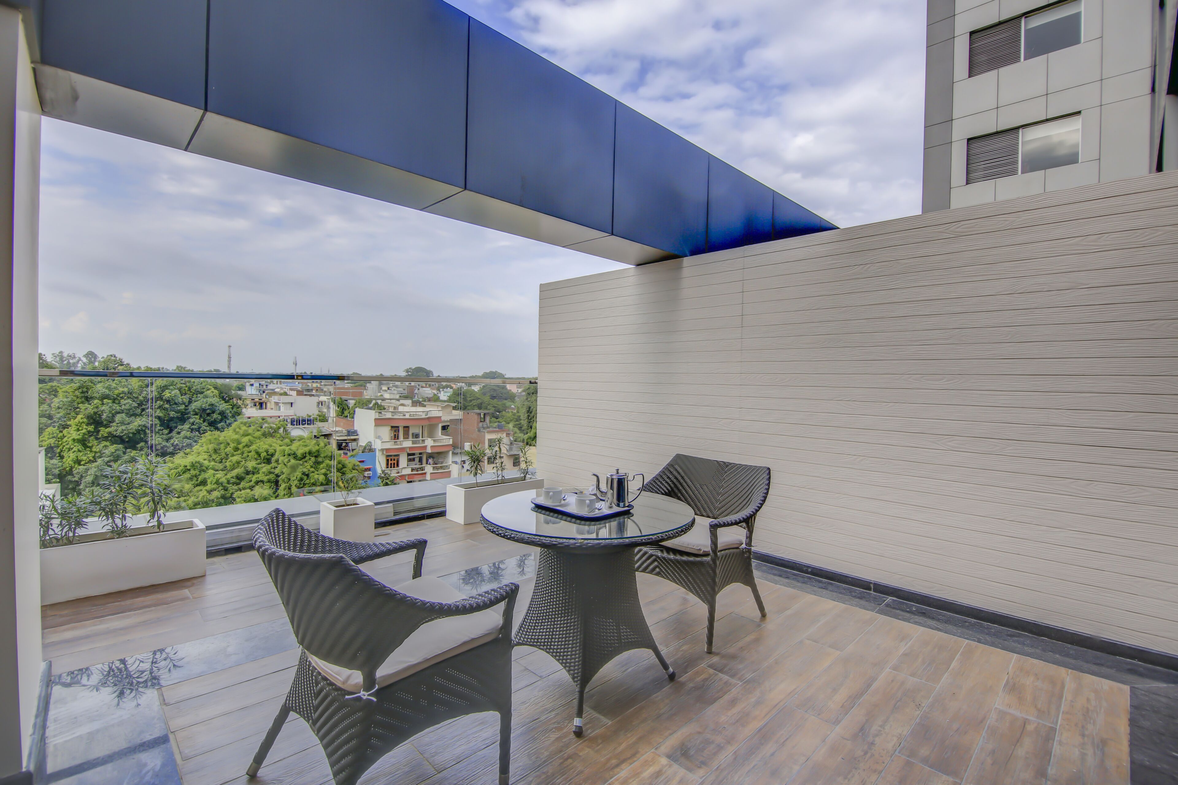 A balcony with a table and chairs, overlooking a cityscape.