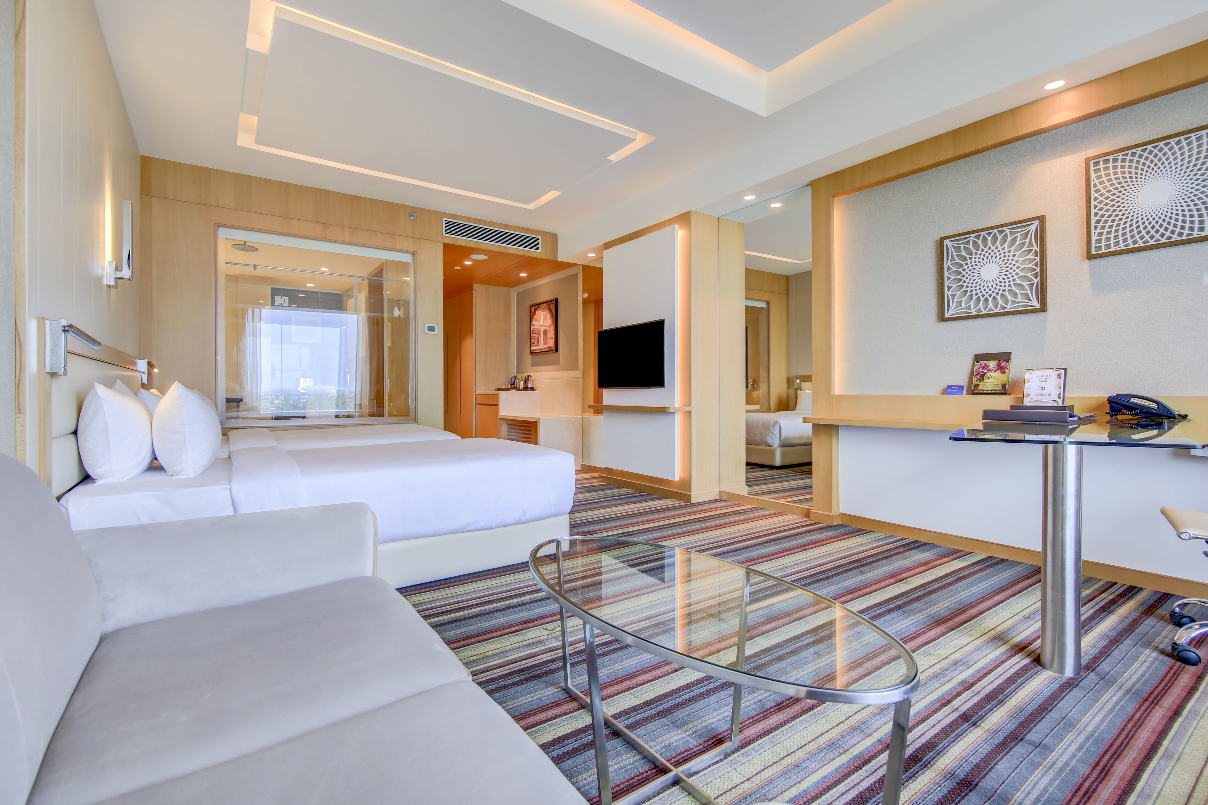 Una habitación de hotel moderna con una cama grande, una zona de estar, un escritorio y un televisor.