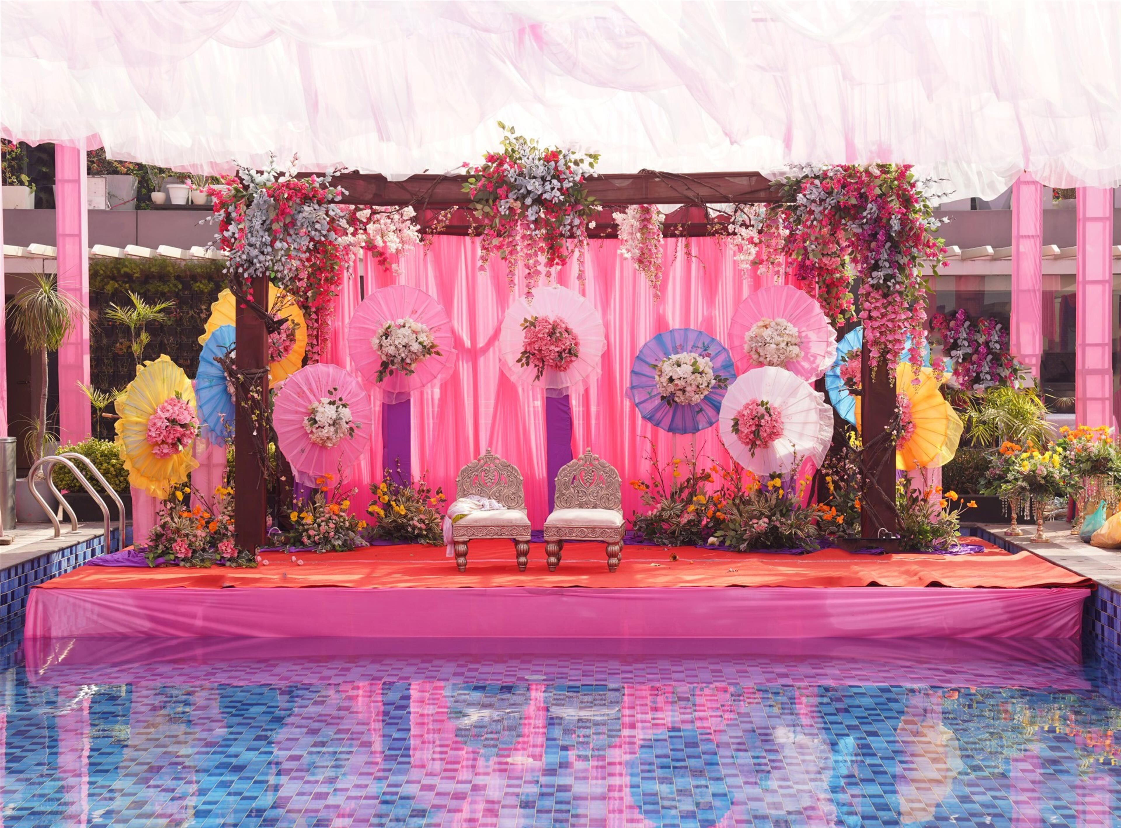 Une scène avec deux chaises blanches, des rideaux roses et des décorations florales.