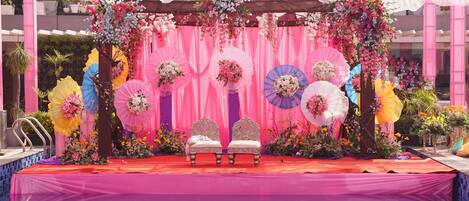 A stage with two white chairs, pink drapes, and floral decorations.