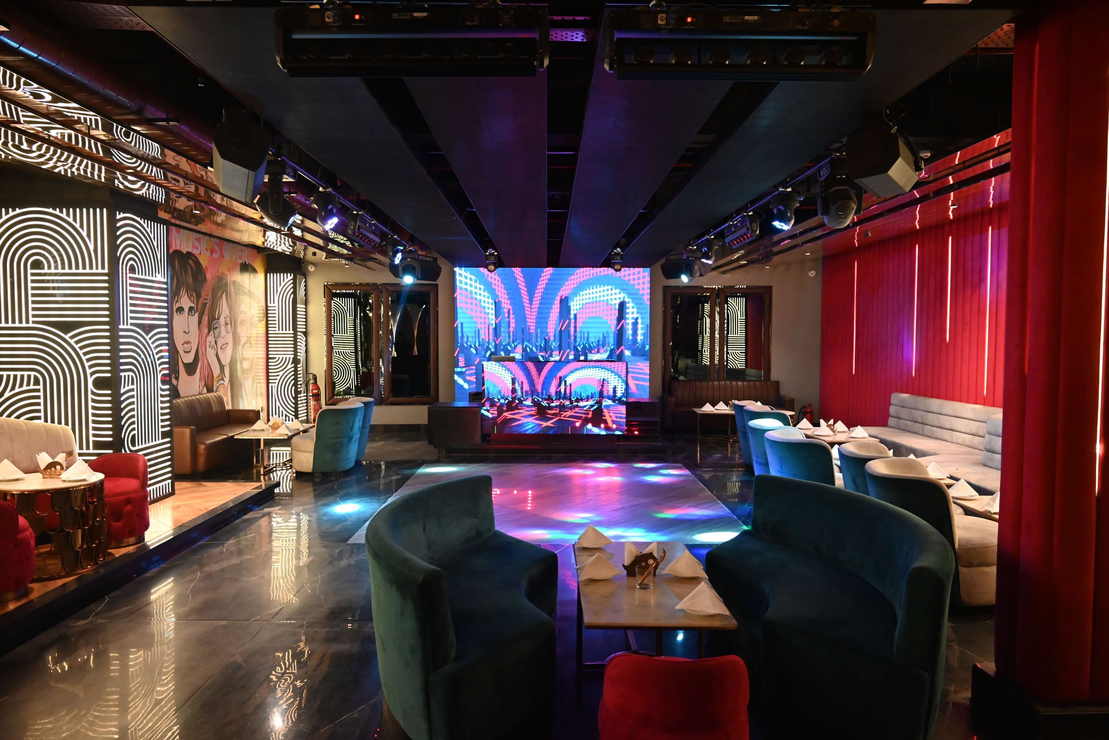 A modern lounge with a central stage, ambient lighting, and plush seating.
