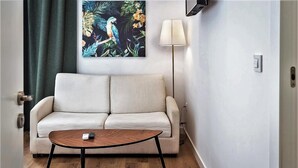 Een woonkamer met een bank, een salontafel en een schilderij van een vogel aan de muur.