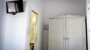 Een kamer met een witte inbouwkast, een flatscreen televisie aan de wand en een deur naar de badkamer.