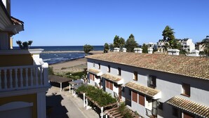 Un bâtiment situé sur la côte, doté d’un toit en tuiles, de balcons et offrant une vue sur la plage et l’océan.