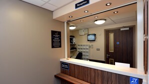 A reception area with a wooden reception desk, a sign for key cards, a reception sign above the desk, a television mounted on the wall, and a door with a blue sign. - Fallow Field, Telford by Marston's Inns (Telford)