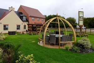 Un pub llamado 'The Fallow Field' con terraza al aire libre y una estructura de pérgola de madera.
