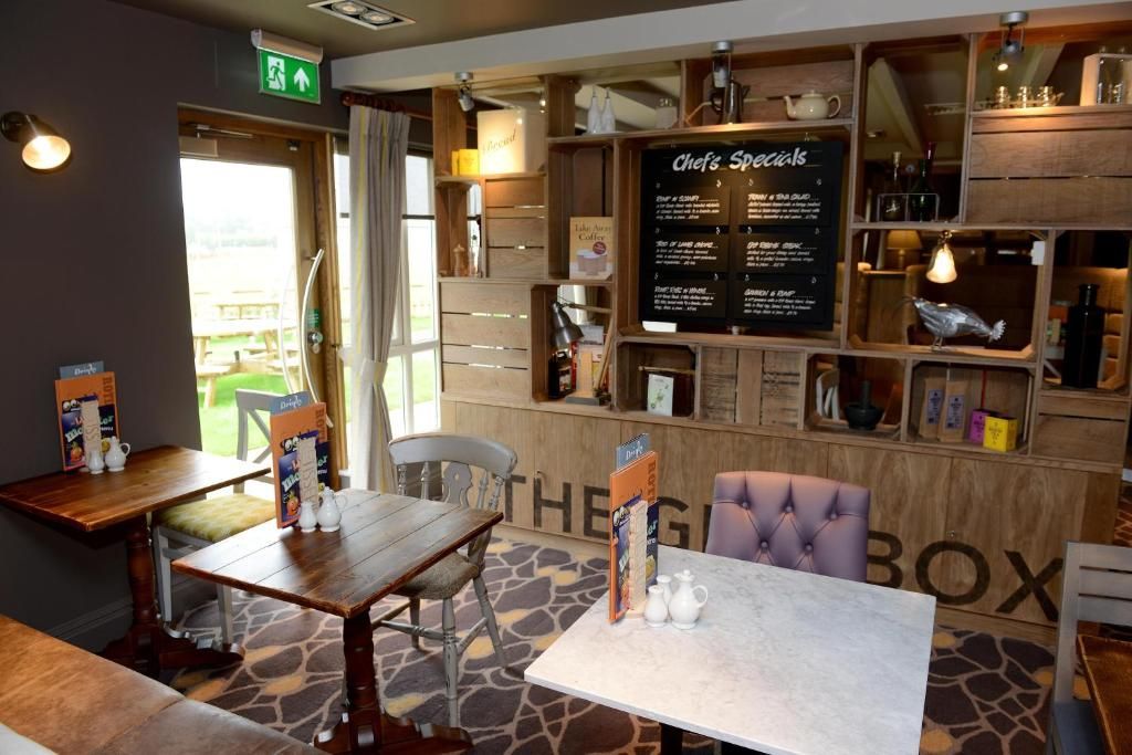 A cozy cafe interior with wooden furniture, a menu board, and a view of the outdoors.