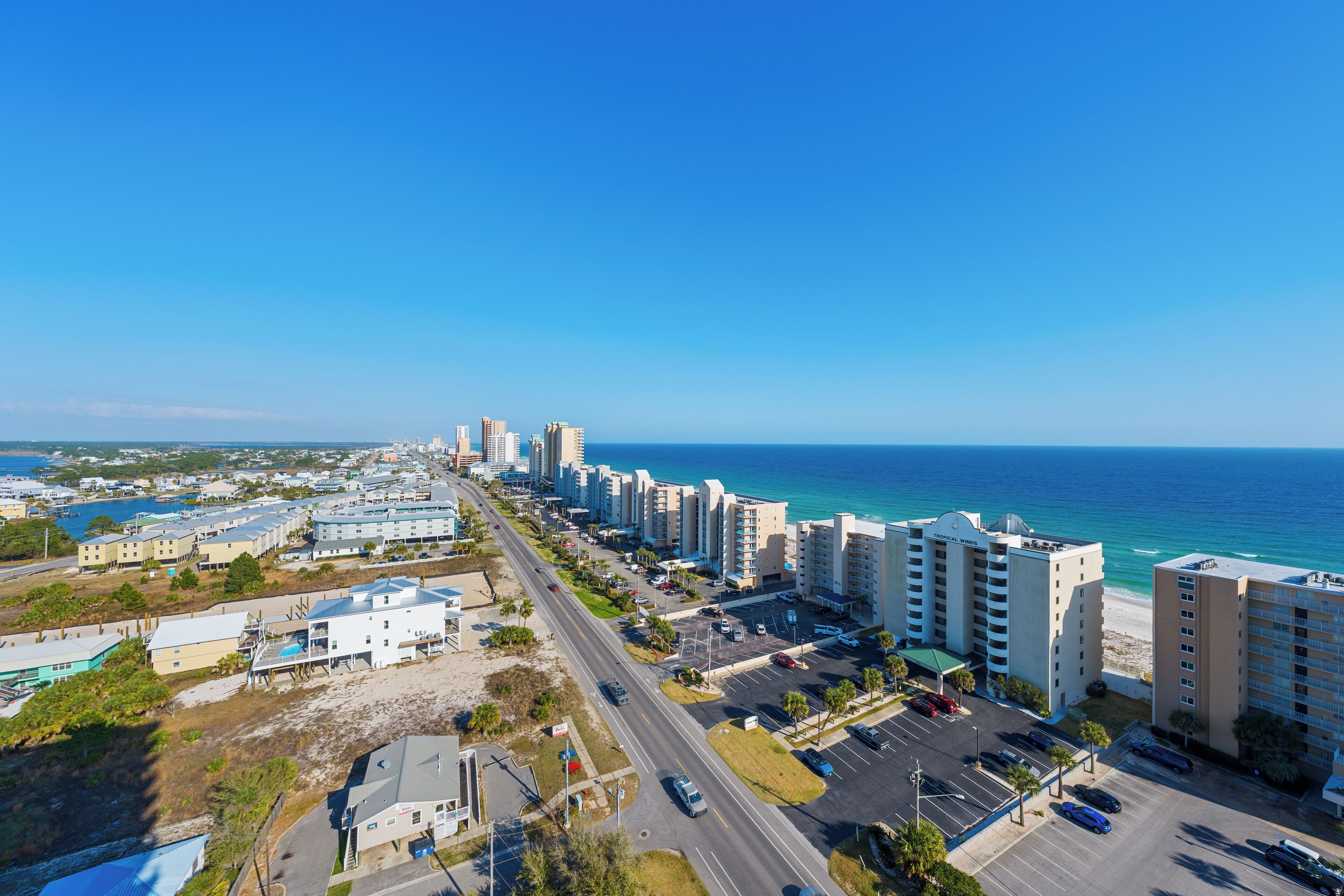 A coastal cityscape with high-rise buildings, a marina, and a clear blue sky.